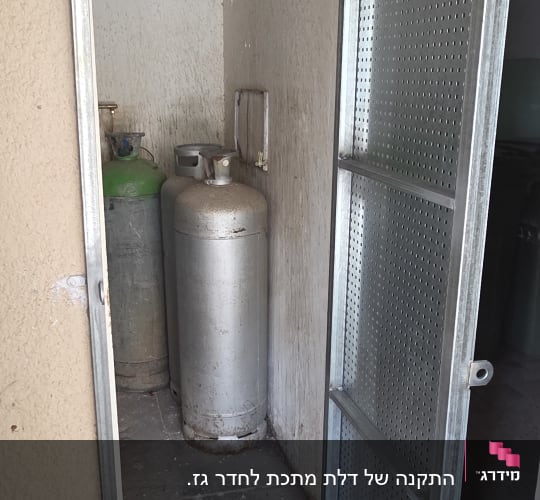 דלת מתכת פתוחה עם בלוני גז מאחוריה